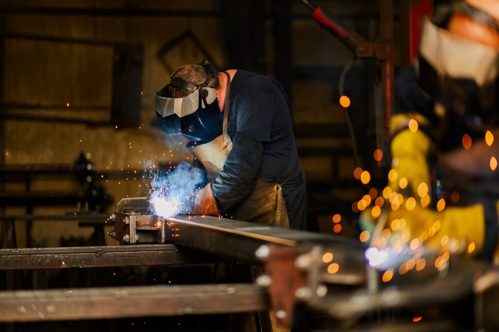 Worker with welding mask and safety gear welding a metal construction.